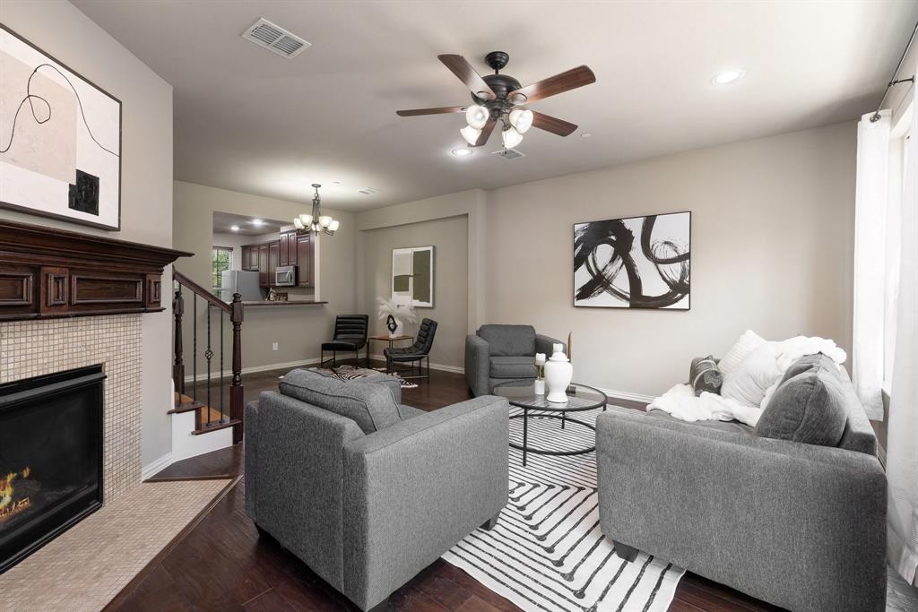 Fireplace with a decorative wood mantel, tiled surround, wood-finish flooring, recessed lighting, and a multi-blade ceiling fan with integrated lighting