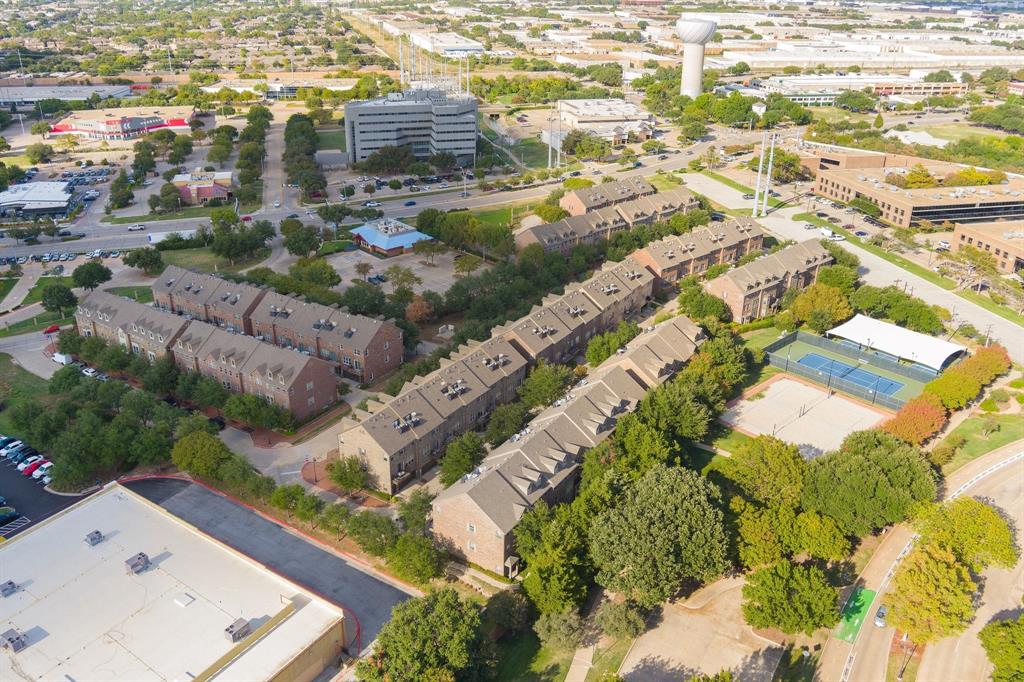 Aerial view of multi-story brick residential structures including a fenced tennis court and recreational area within the property grounds