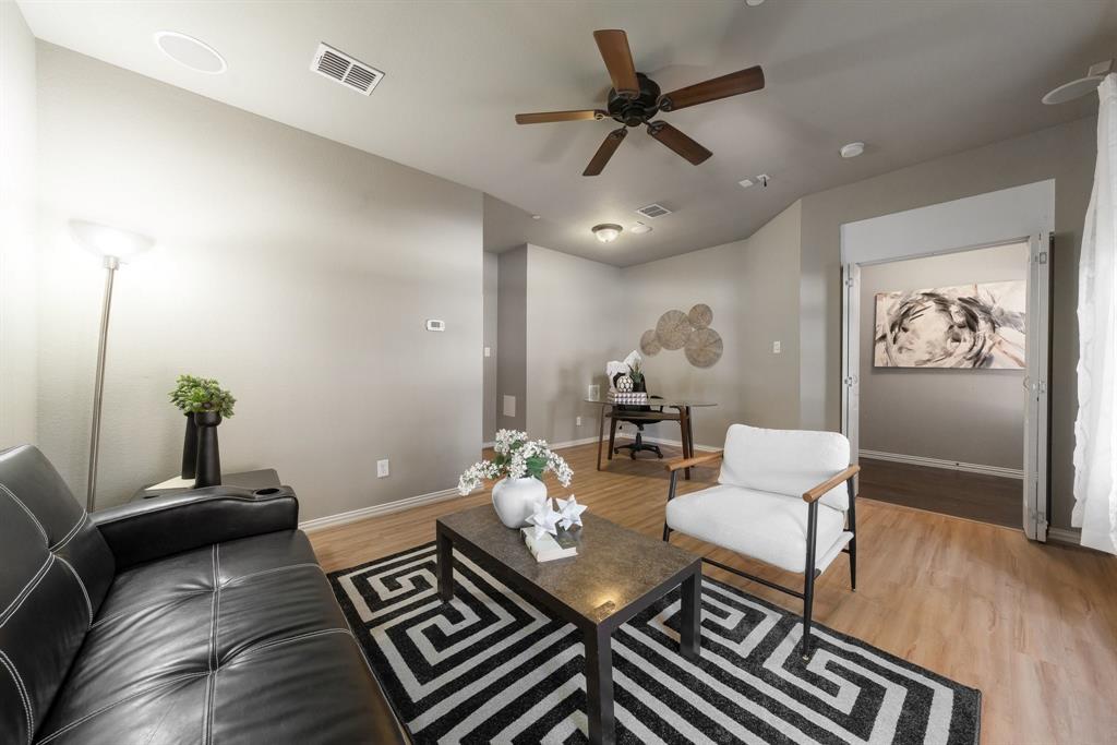 Neutral-toned interior space featuring wood-finish flooring, a ceiling fan, and folding interior doors