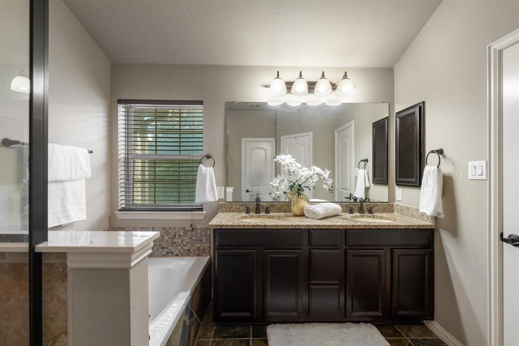 Double vanity with dark wood-finish cabinetry, stone-style countertops, integrated dual sinks, and a large wall-mounted mirror