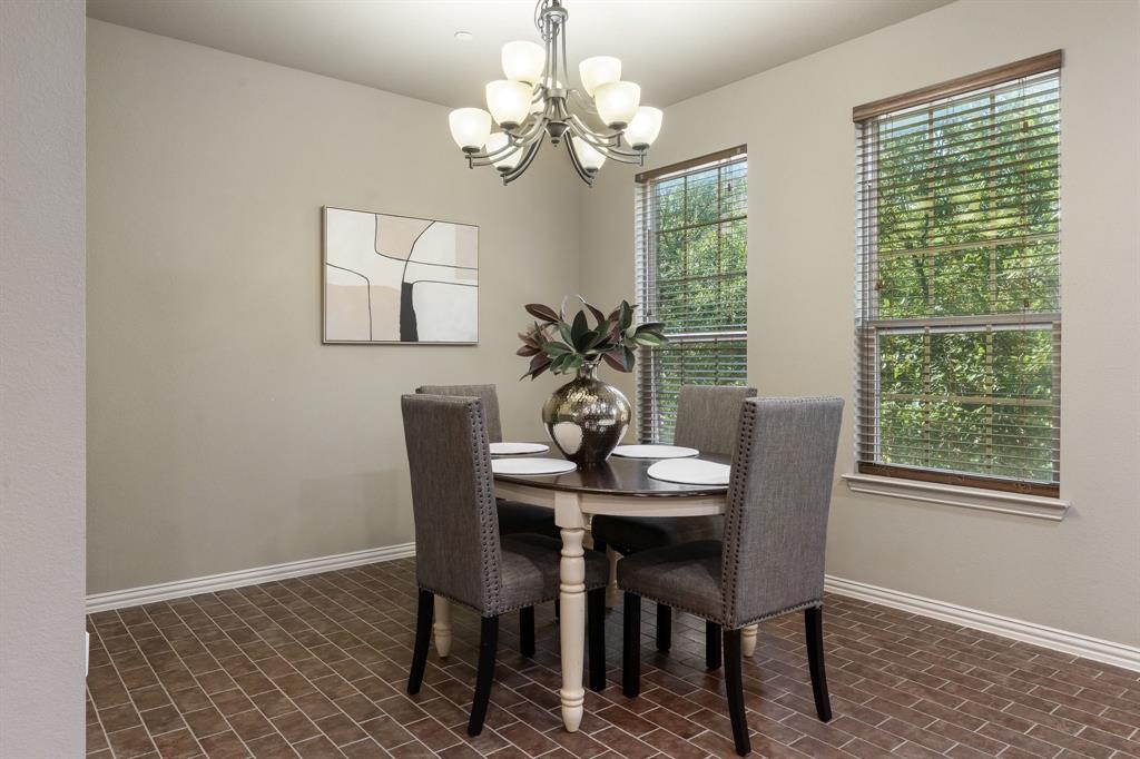 Dining area featuring brick-style tile flooring, multi-light chandelier with glass shades, and two windows with slatted blinds