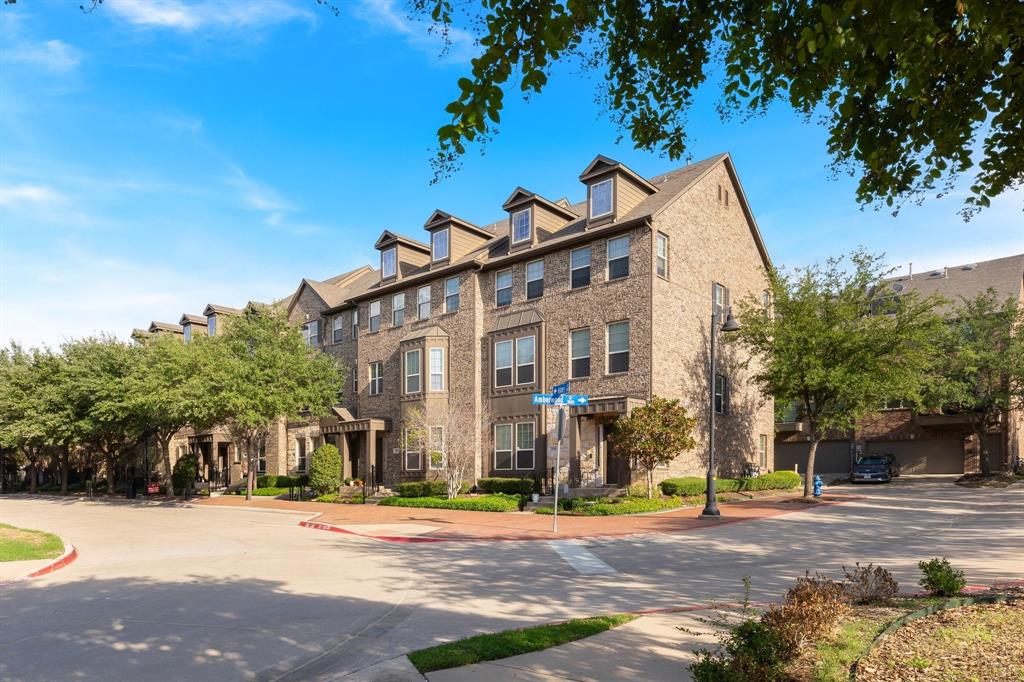 Multi-story brick exterior featuring dormer windows, bay architectural detailing, and paved walkways