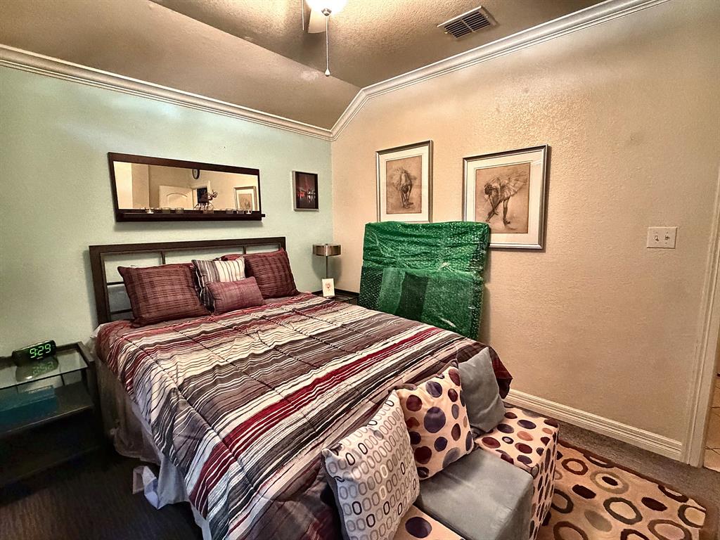 Vaulted ceiling with crown molding and a centrally mounted ceiling fan