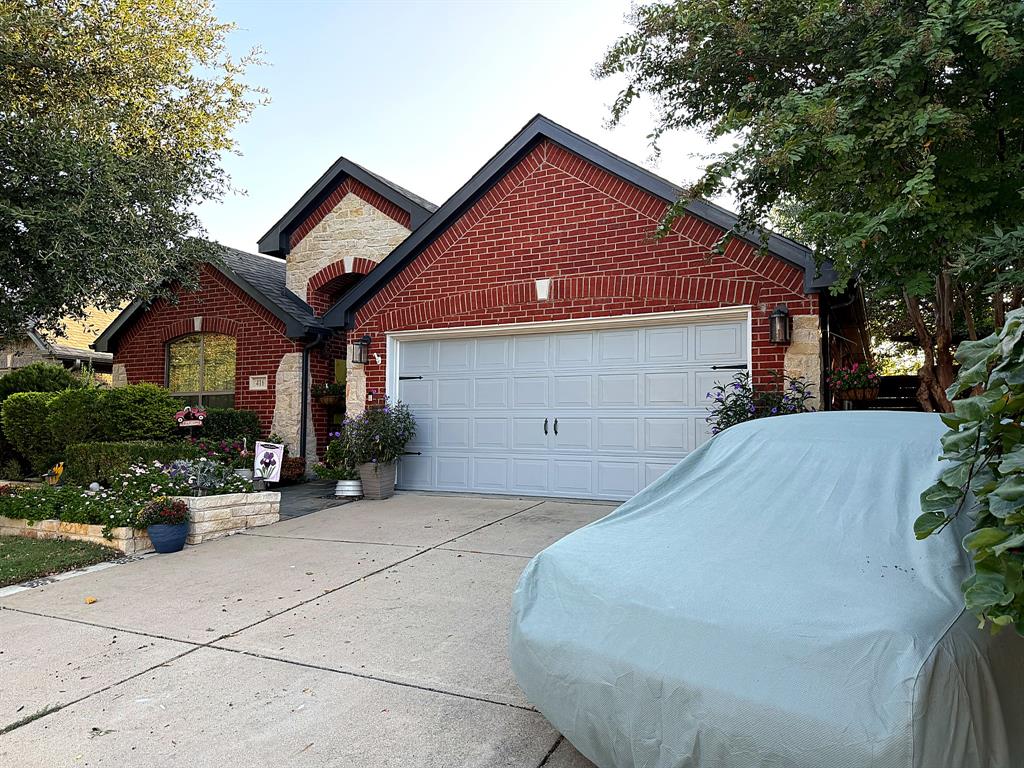 Exterior facade featuring red brick masonry, natural stone accents, a multi-gabled roofline, and an attached two-car garage