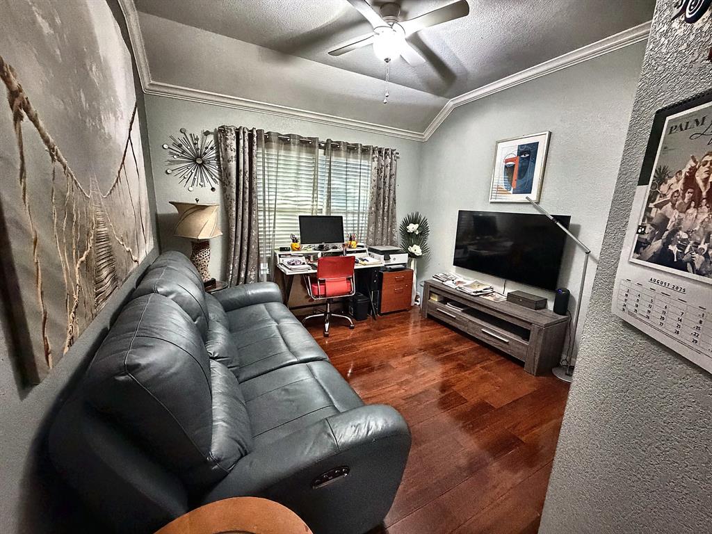 Room featuring wood-finish flooring, vaulted ceilings, and a central ceiling fan with integrated lighting