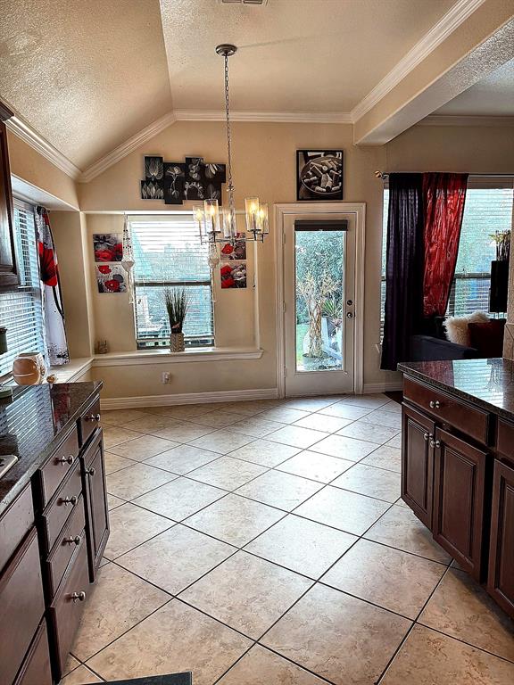 Vaulted ceiling, built-in window seating, tile flooring, multi-light chandelier, and glass-paneled exterior door