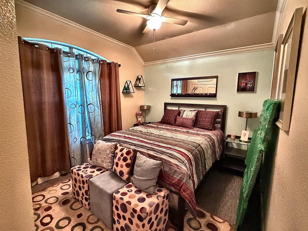 Vaulted ceiling featuring crown molding, arched window, and a central ceiling fan with integrated lighting