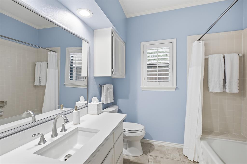 Hall bath with a quartz vanity, plantation shutter, and a calming blue palette.