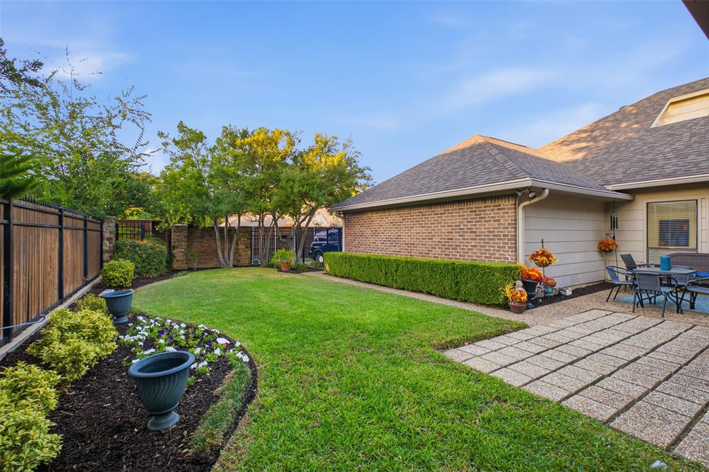 A green, private backyard enclosed by a wood-and-iron fence with stone columns—your own backyard escape.