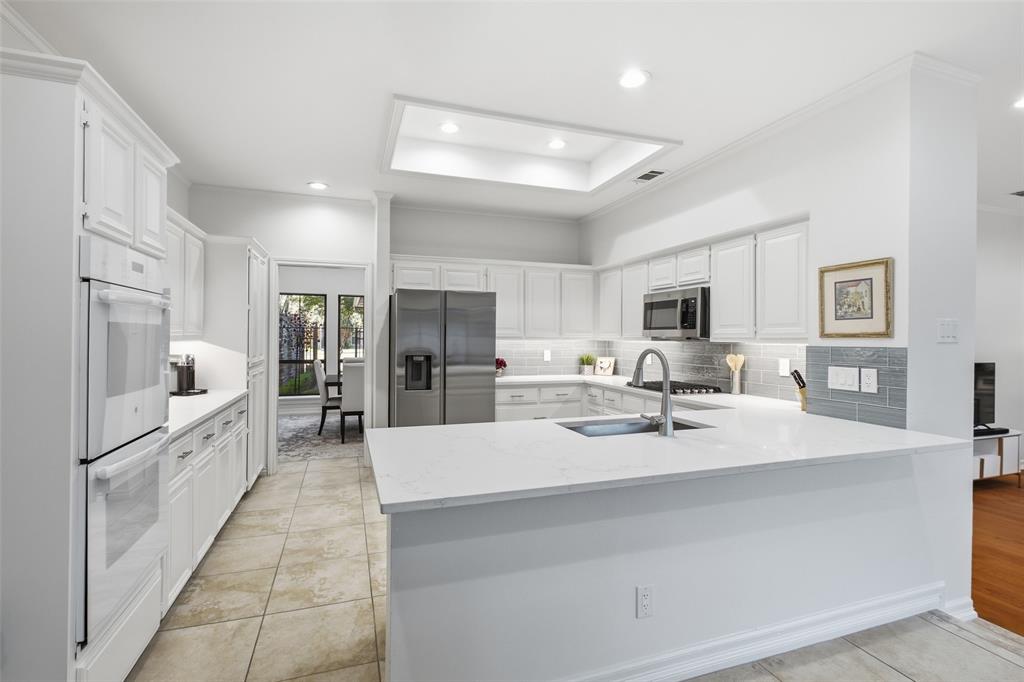 Double wall ovens, abundant white cabinetry, and a sprawling quartz peninsula give the home chef room to create.