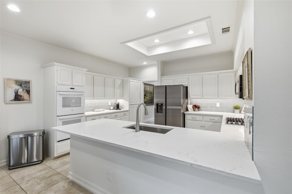 Quartz countertops, gray subway tile, and a lighted tray ceiling—a kitchen as pretty as it is practical.