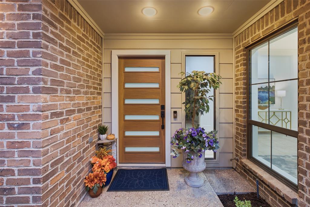 A modern wood-and-glass front door with sidelight sets a fresh, stylish tone at the covered front entry.