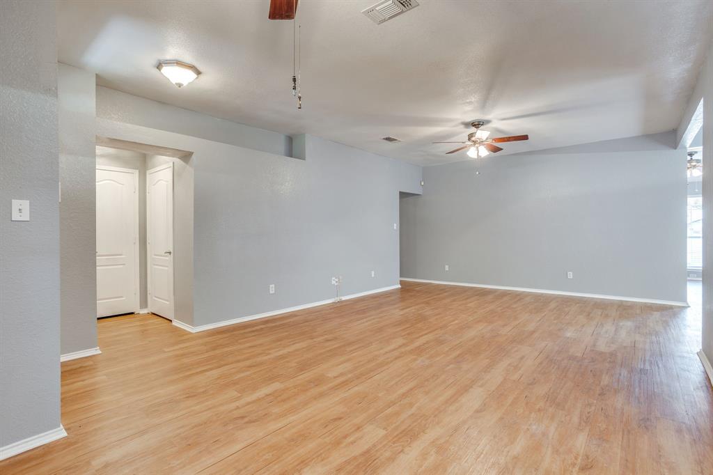 Open-concept interior featuring wood-finish flooring, dual ceiling fans, flush-mount lighting, and solid-core interior doors