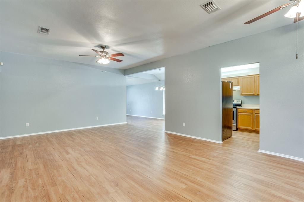 Open-concept area featuring wood-finish flooring, vaulted ceilings, and dual ceiling fans
