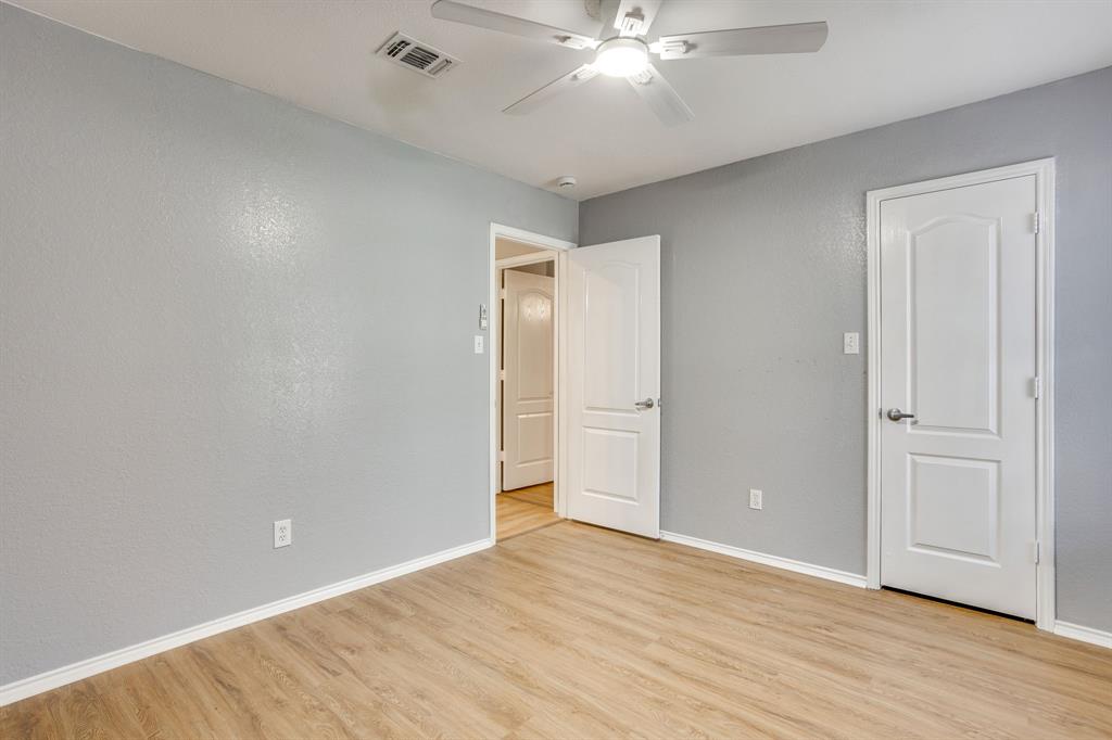 Neutral-toned walls paired with light-finish wood-finish flooring, featuring a ceiling fan with integrated lighting and interior doors with two-panel architectural detailing