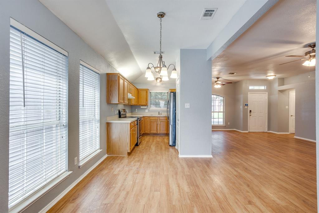 Kitchen area featuring wood-finish cabinetry, solid-surface countertops, a suspended multi-light chandelier, and wood-finish flooring