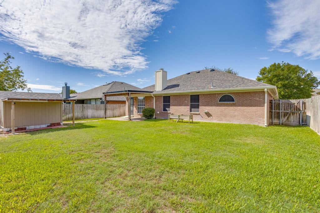 Brick exterior residence featuring a covered patio, a detached storage structure, and a fenced backyard