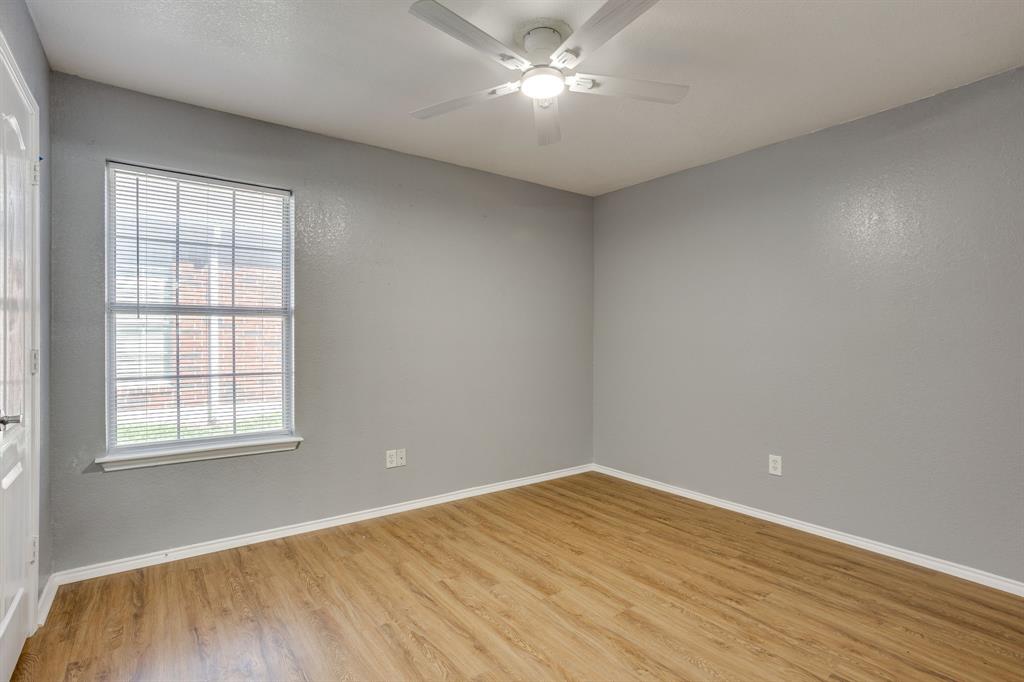 Neutral-toned interior featuring wood-finish flooring, a ceiling fan with integrated lighting, and a window with horizontal blinds