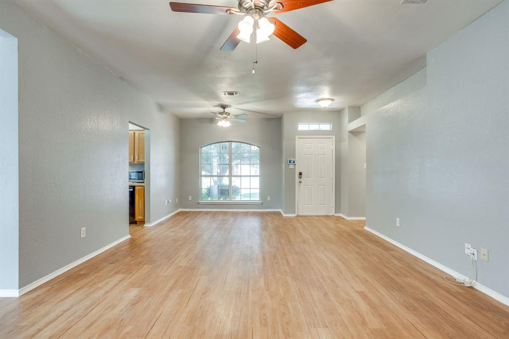 Open interior featuring wood-finish flooring, two ceiling fans, and an arched window