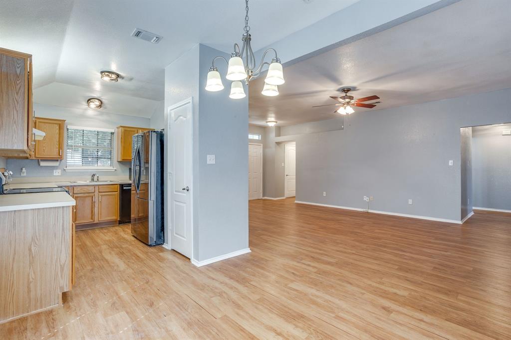 Kitchen featuring wood cabinetry, solid-surface countertops, and wood-finish flooring, complemented by an ornate multi-arm chandelier and recessed ceiling lighting