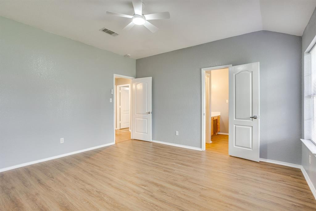 Room featuring vaulted ceilings, wood-finish flooring, and a ceiling fan with integrated lighting