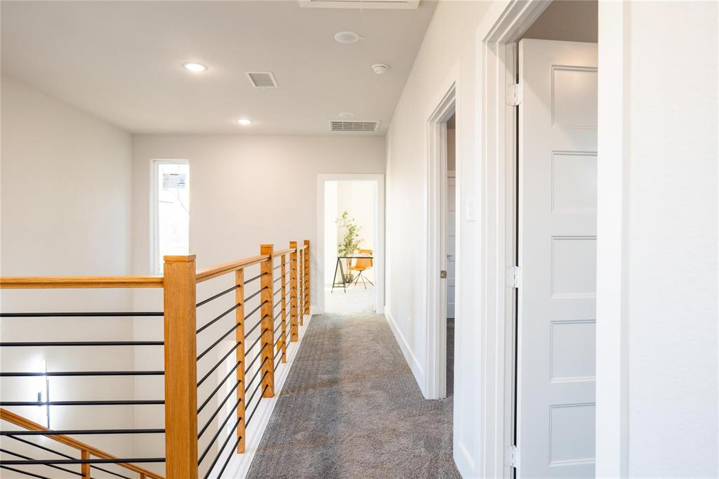 Hallway featuring carpeting, recessed lighting, and a stair railing composed of wood posts with horizontal metal balusters, accompanied by five-panel interior doors