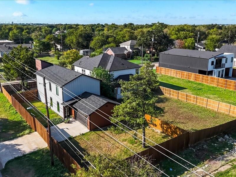 Aerial perspective of multi-level exterior featuring vertical siding, a composition shingle roof, a concrete driveway, and enclosed backyard fencing