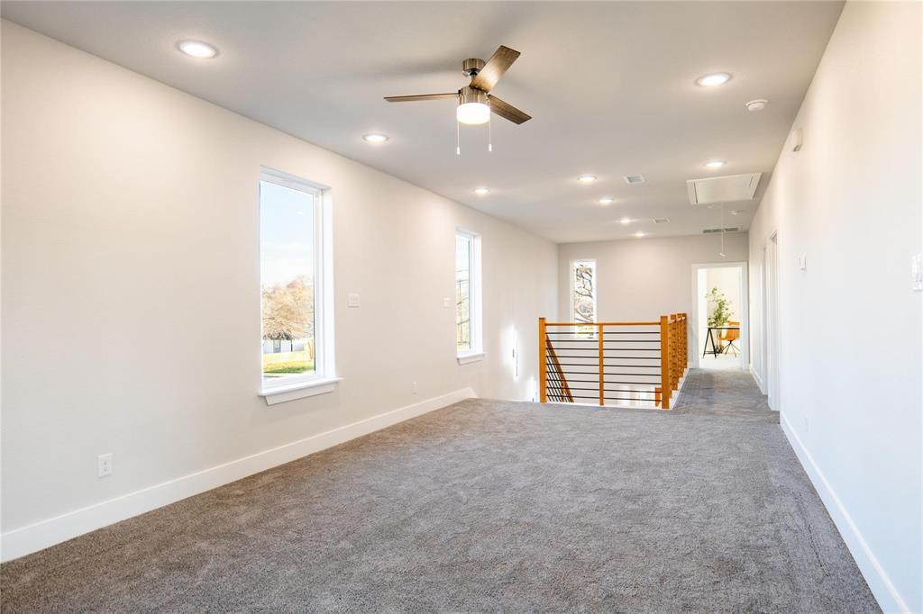 Interior space featuring recessed lighting, a ceiling fan, neutral carpeting, and a wooden staircase railing with horizontal metal balusters