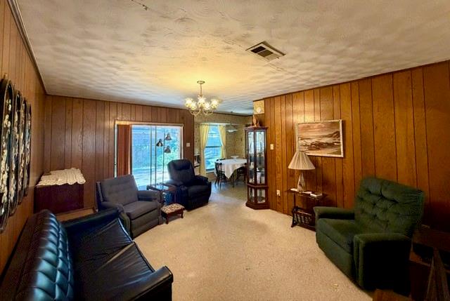 Interior space featuring floor-to-ceiling wood paneling, textured ceiling, multi-light chandelier, and glass sliding door
