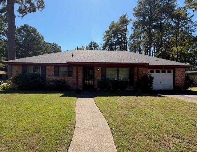 Single-story brick exterior featuring a hip roof, covered porch entry, concrete walkway, and an attached garage