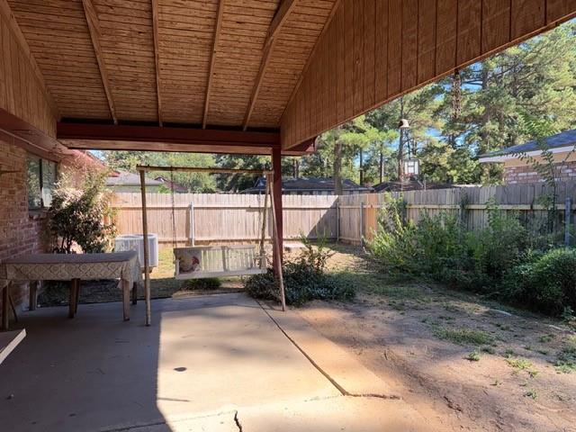 Covered patio featuring a wood-plank ceiling, concrete flooring, and a fenced backyard