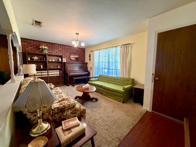Exposed brick accent wall, multi-pane window with full-length drapery hardware, decorative columns, and tile flooring