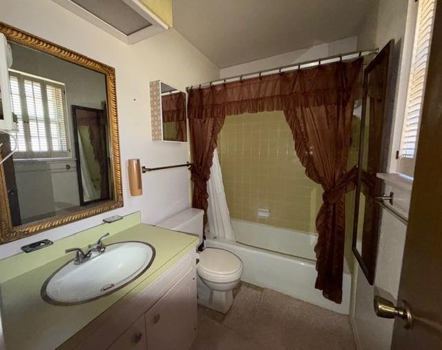 Bathroom featuring a vanity with a recessed sink and solid-surface countertop, a tub-and-shower combination with tiled surround, a wall-mounted mirror, and louvered window shutters