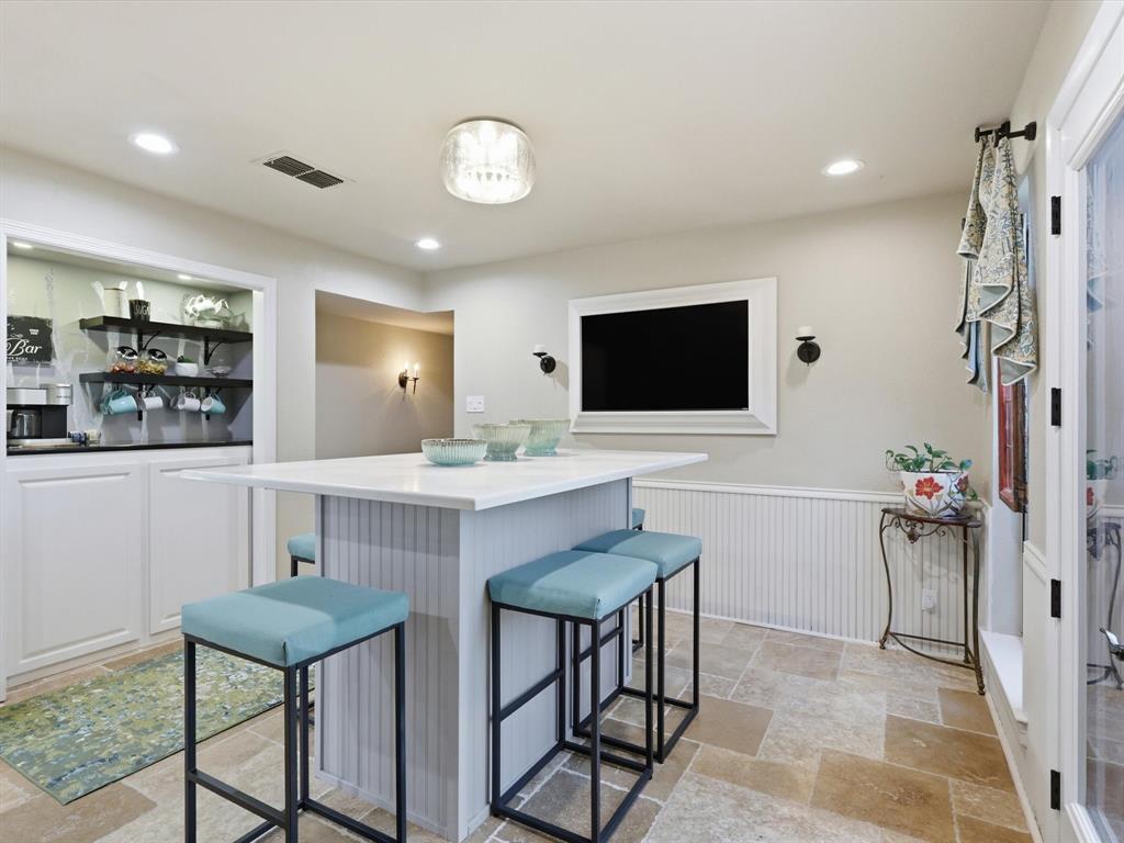 Built-in cabinetry with open shelving, stone-finish tile flooring, beadboard wall paneling, and recessed ceiling lighting
