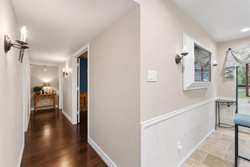 Interior corridor featuring wood-finish flooring, white beadboard wainscoting, and wall-mounted candle-style sconces
