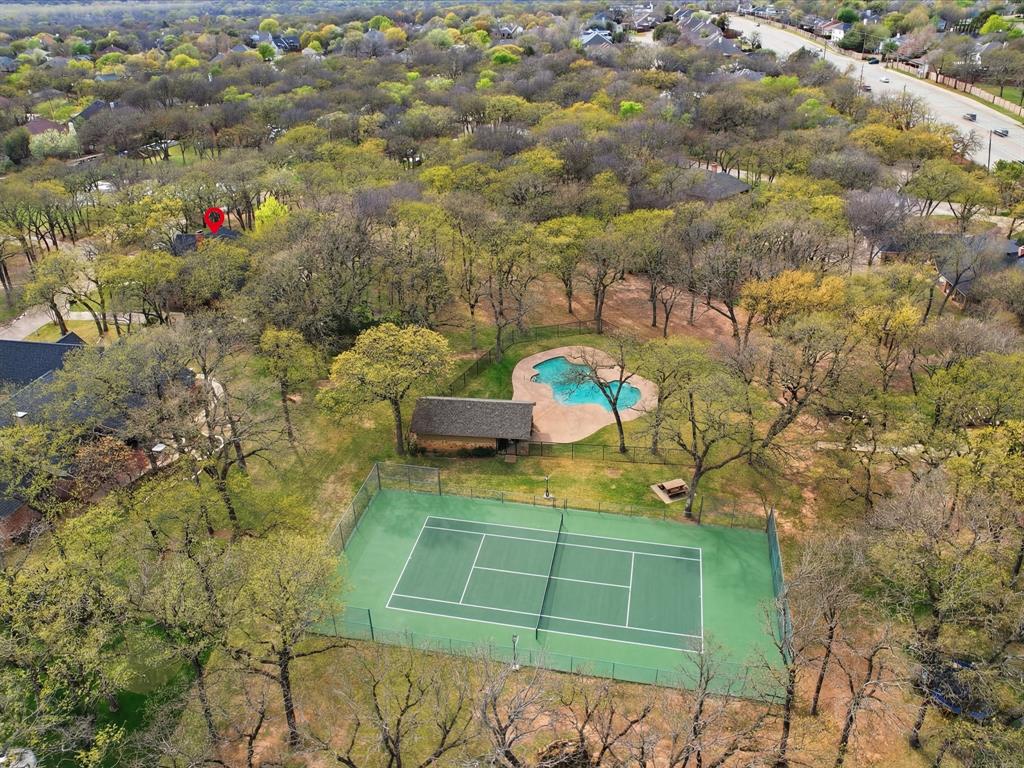 Expansive grounds featuring a fenced tennis court, swimming pool, detached structure, and mature trees