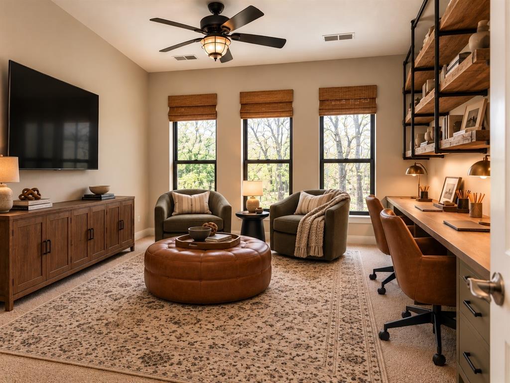 Built-in wooden desk with integrated cabinetry, floor-to-ceiling industrial-style wall shelving, three large windows with woven wood shades, and a ceiling fan with integrated lighting