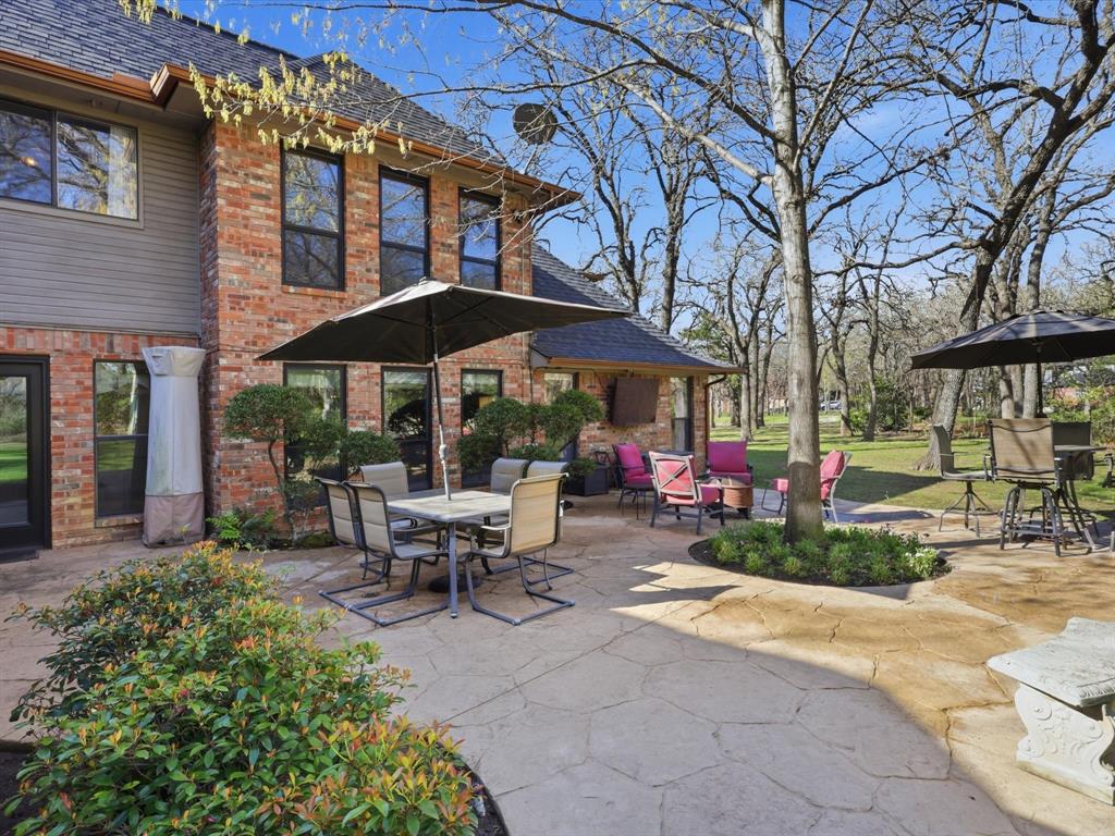 Flagstone patio featuring mature trees, mixed-media brick and siding exterior, and integrated landscape beds