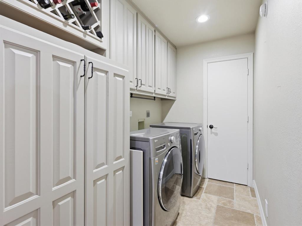Custom cabinetry with integrated wine storage, upper and lower storage units, and stone-tile flooring