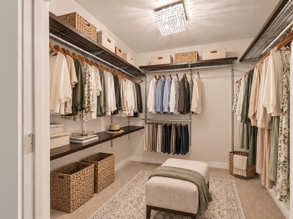 Walk-in closet featuring multi-tiered adjustable shelving, integrated hanging rods, wall-to-wall carpeting, and a flush-mount crystal-style light fixture