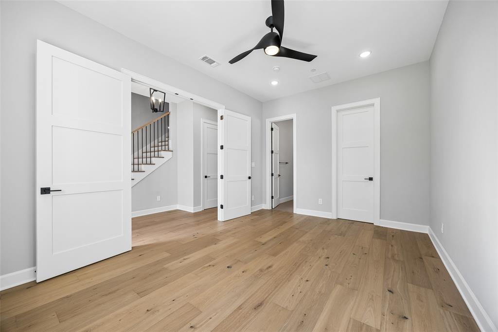 Interior space featuring wood-finish flooring, three-panel solid core doors, matte black hardware, and a modern three-blade ceiling fan