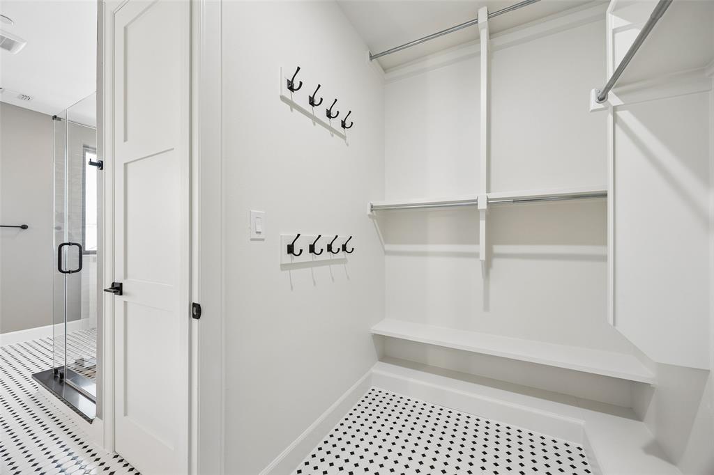 Walk-in closet featuring white built-in shelving, dual-tier hanging rods, and mounted hardware hooks