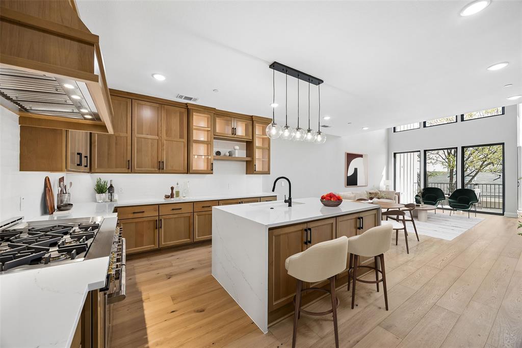 Kitchen featuring wood cabinetry, quartz countertops, a central island with a matte black faucet, and wood-finish flooring