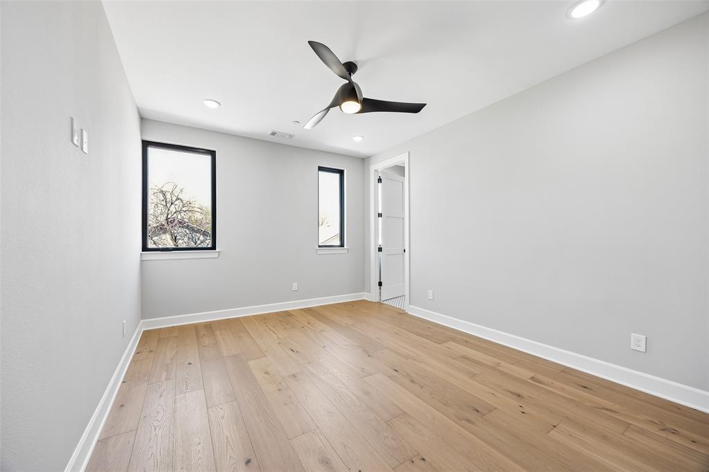 Interior space featuring wood-finish flooring, recessed lighting, a modern three-blade ceiling fan, and windows framed by black casings