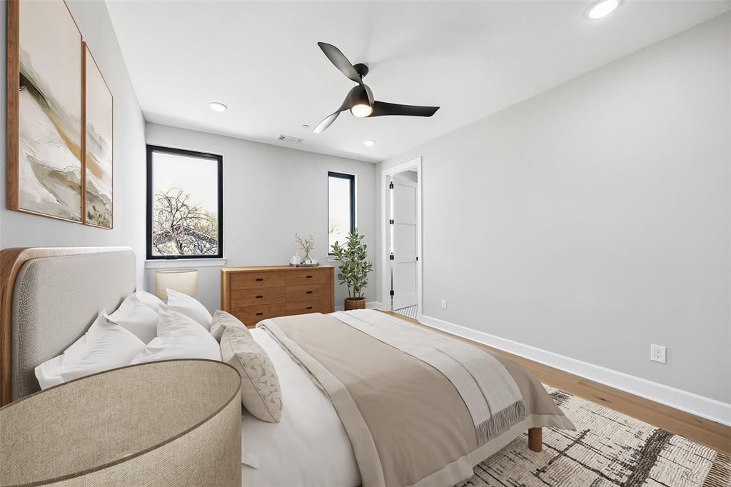 Neutral walls, wood-finish flooring, recessed lighting, matte black-framed windows, and a multi-blade ceiling fan
