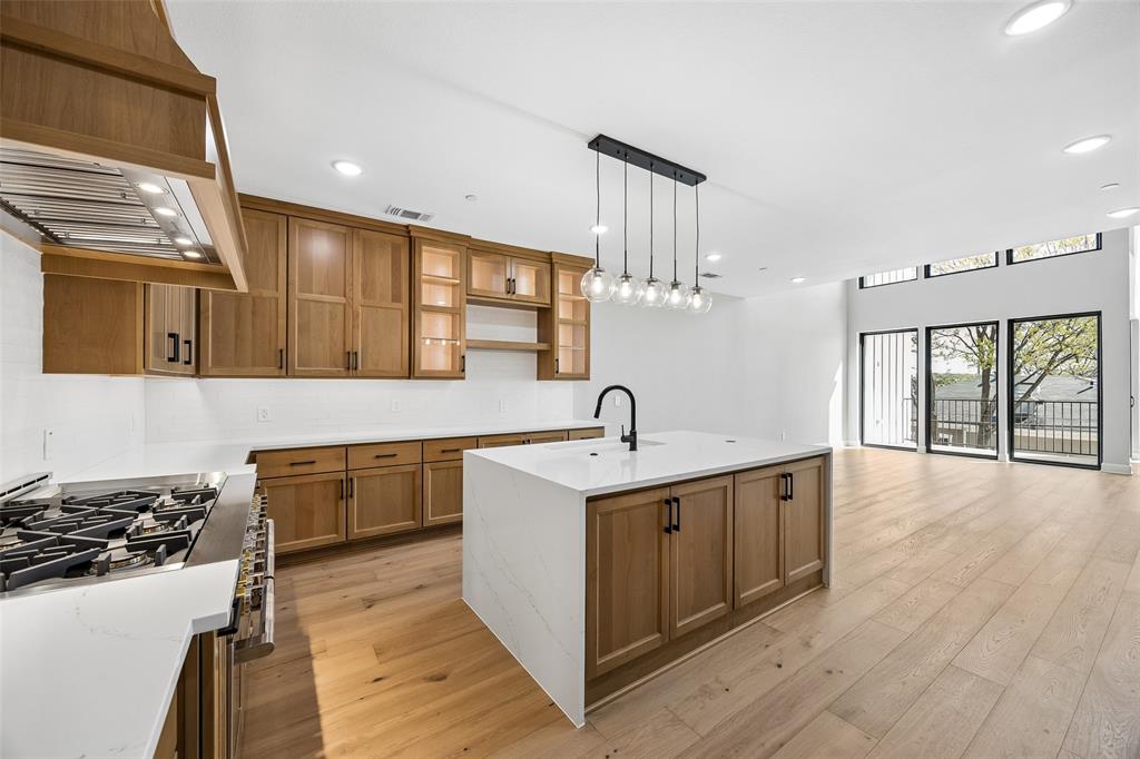 Kitchen featuring wood-finish cabinetry, a central island with a quartz countertop, recessed lighting, wood-finish flooring, and a multi-pendant light fixture