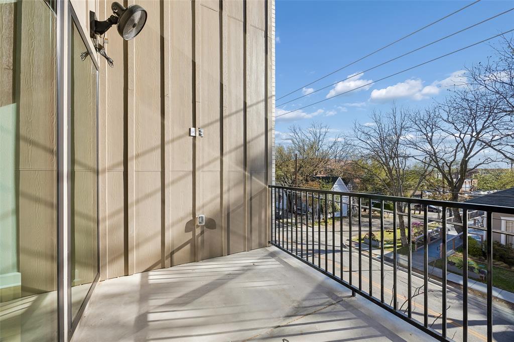 Balcony featuring vertical board-and-batten siding, a black metal railing, and an attached exterior light fixture