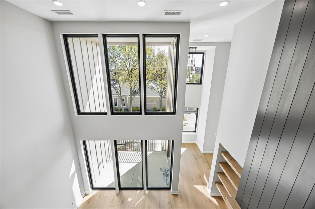 Two-story vaulted ceiling with expansive windows, wood-finish flooring, floor-to-ceiling metal wall paneling, and built-in wall shelving