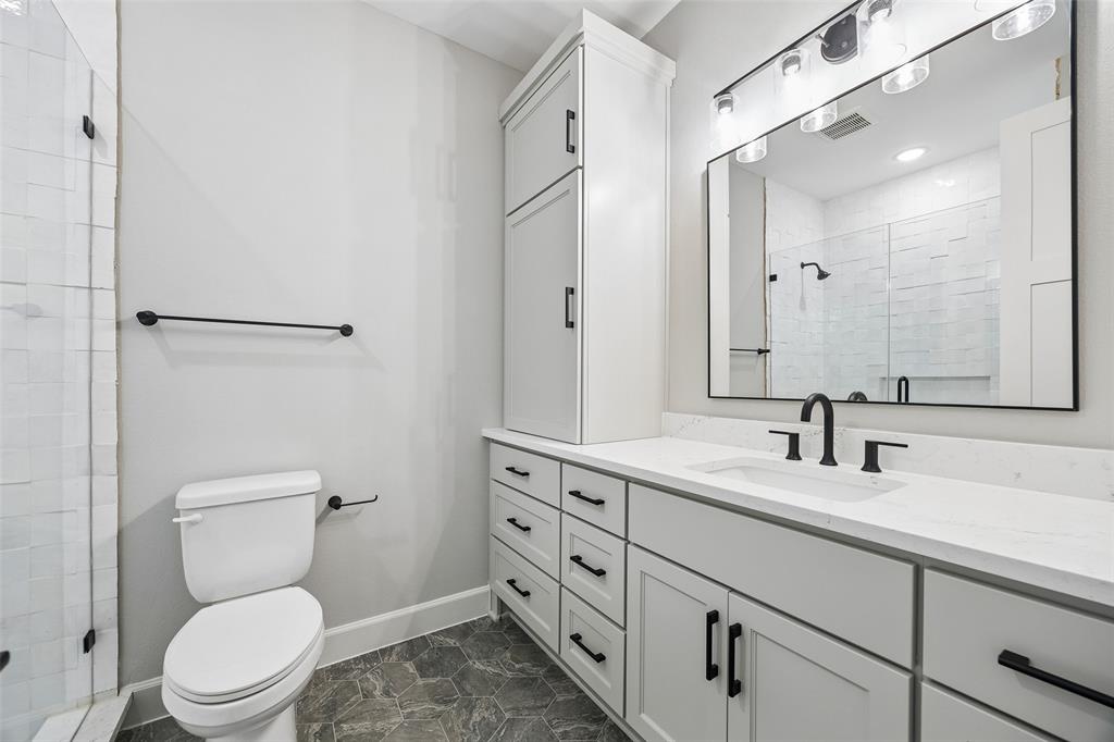 Bathroom featuring a light-toned vanity with integrated cabinetry, solid surface countertop, matte black fixtures, and hexagonal floor tiling