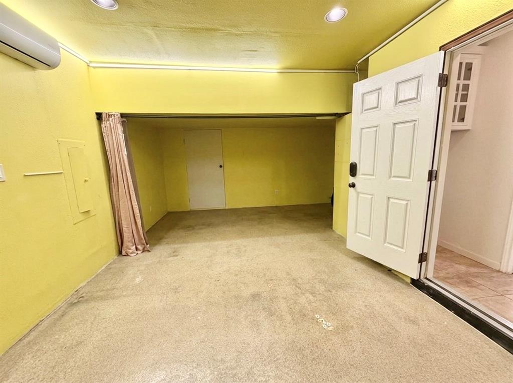 Interior space featuring a wall-mounted ductless HVAC unit, recessed ceiling lighting, a six-panel exterior door, and concrete flooring